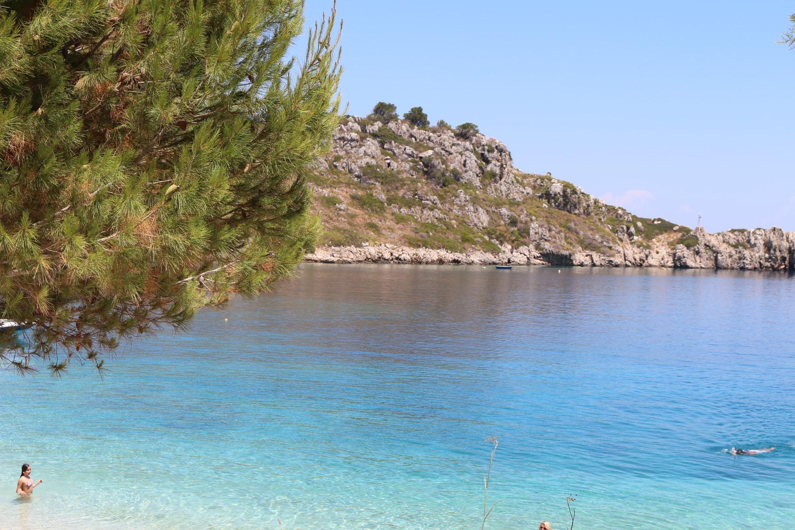 A small cove with incredibly clear, transparent turquoise water revealing the rocky seabed below.