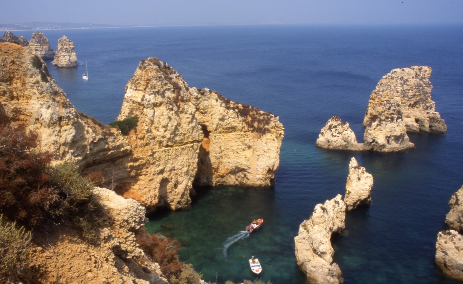 An aerial view of the Ponta da Piedade headland shows dramatic golden sea stacks and arches in turquoise water.