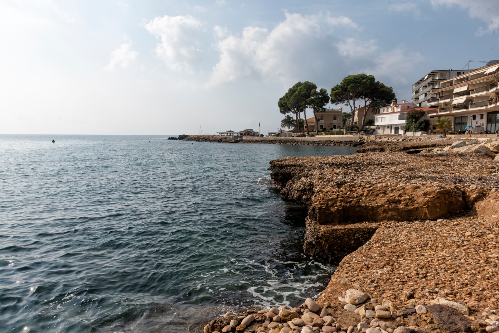 View from Playa de l'Olla looking towards the rocky headland of Cap Negret, showing the built-up coastline of Altea.