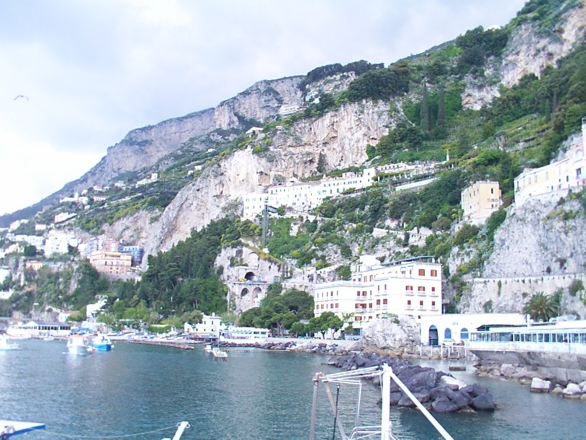 A view of the Amalfi Coast's cliffs, harbors, and buildings from the sea.