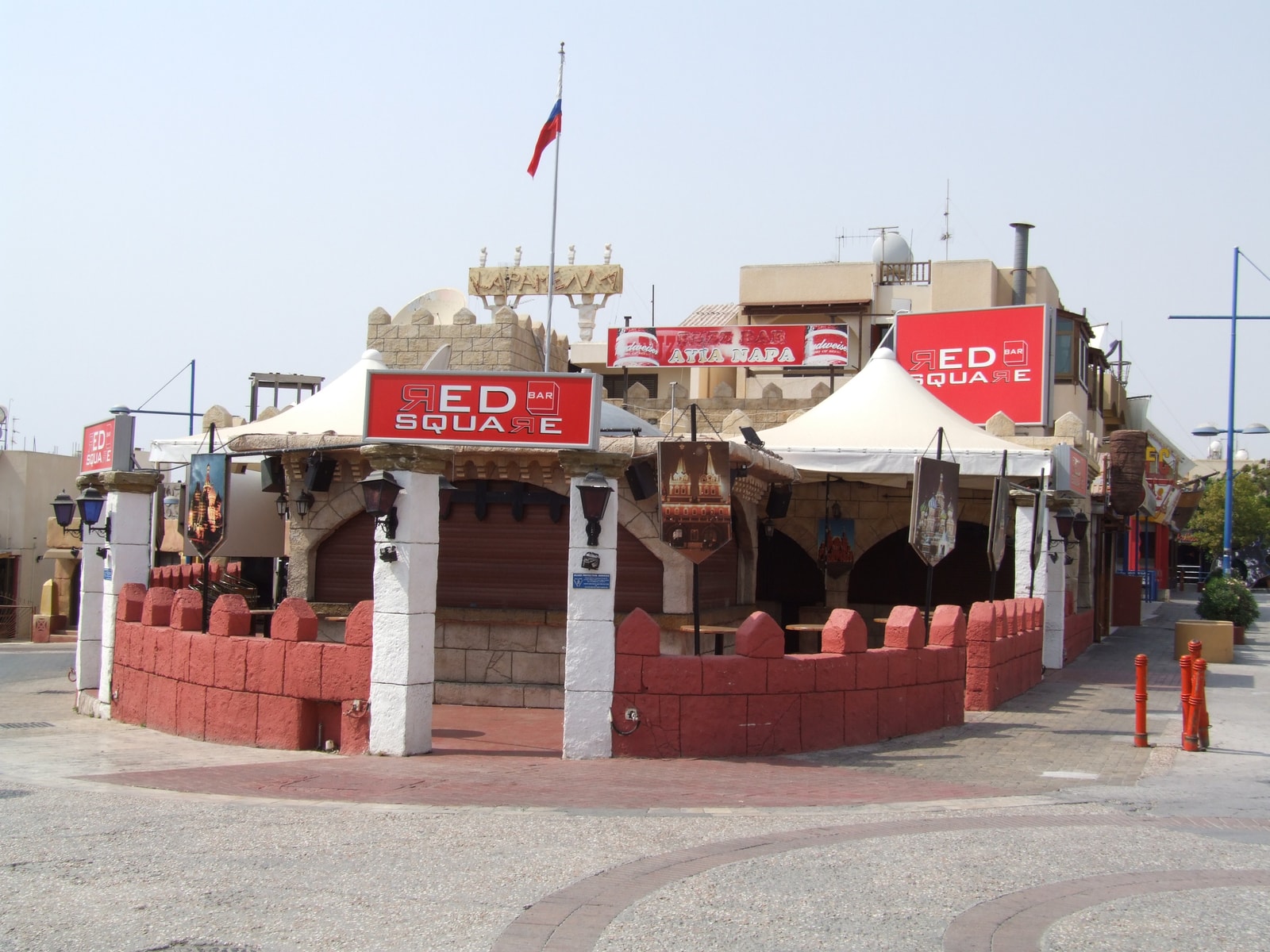 The castle-like brick facade of the Red Square Bar in Ayia Napa's entertainment district at night, lit with red lights.