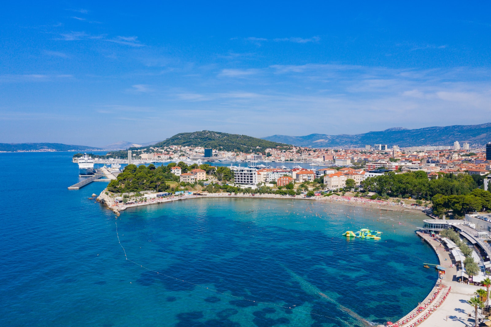 Aerial perspective looking over Bačvice's crescent-shaped bay with Split city structures rising in the background.