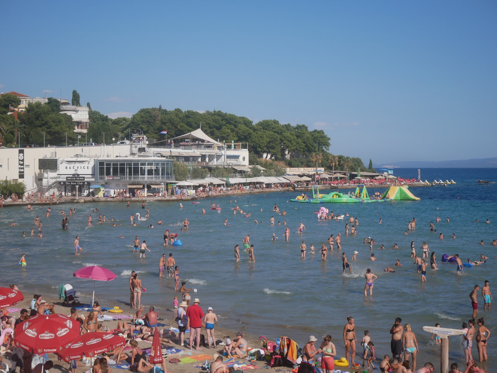 Ground level view of crowds on the sand at Bačvice Beach, with the multi-level pavilion rising directly behind them.