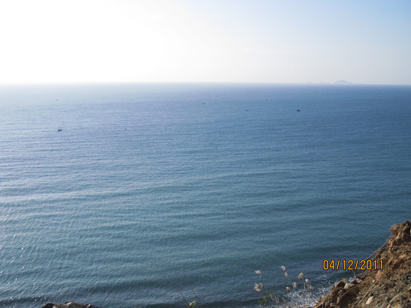 A hazy, wide-angle view of a long, open coastline with a road running alongside it.