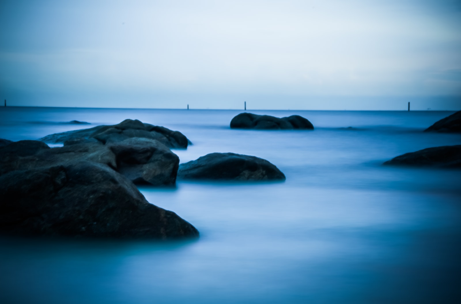 A long-exposure shot of a calm sea at Bang Saen with dramatic, moody clouds overhead.