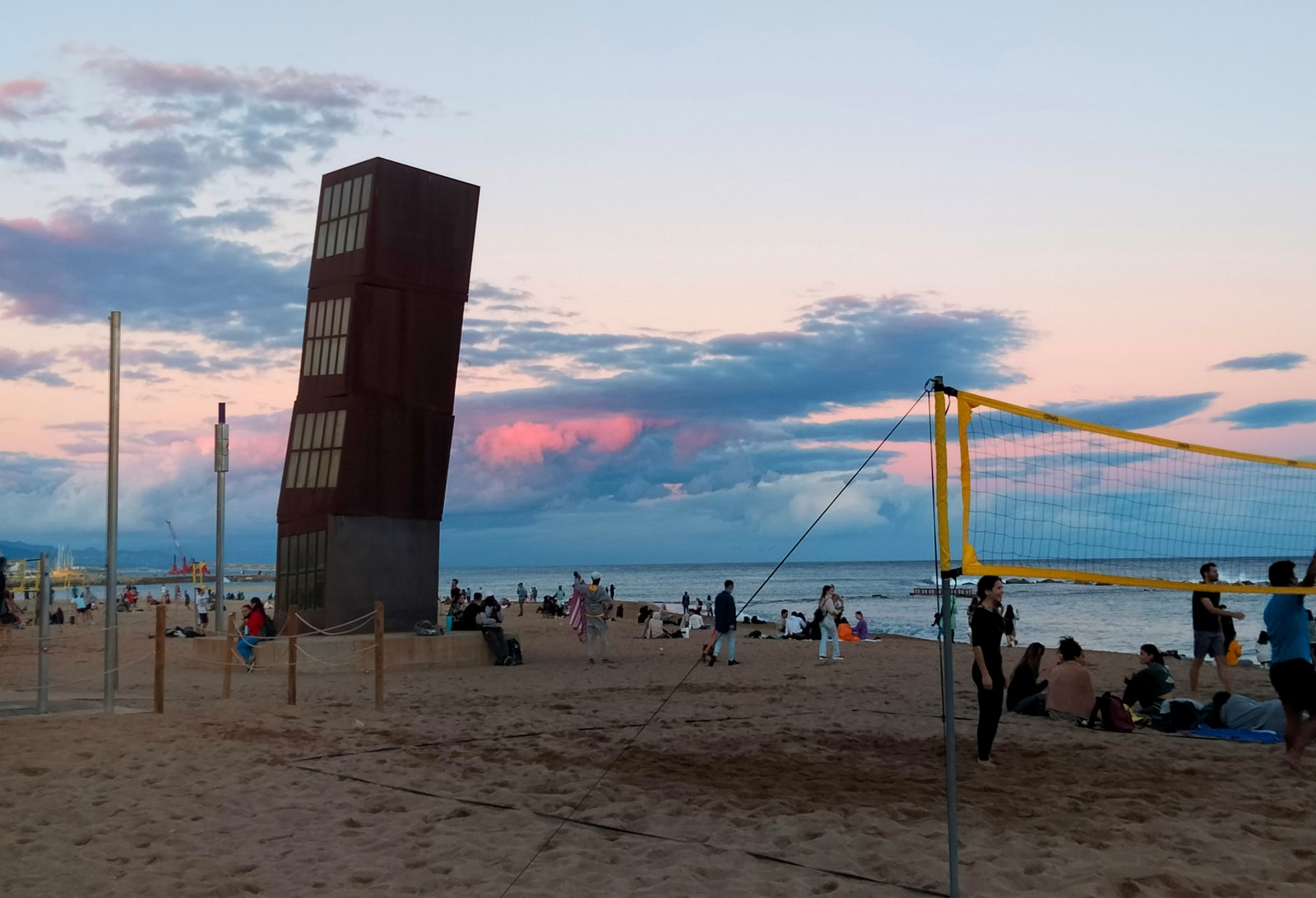 A beach volleyball net is set up on the sand at Platja de Sant Miquel during a beautiful sunset.