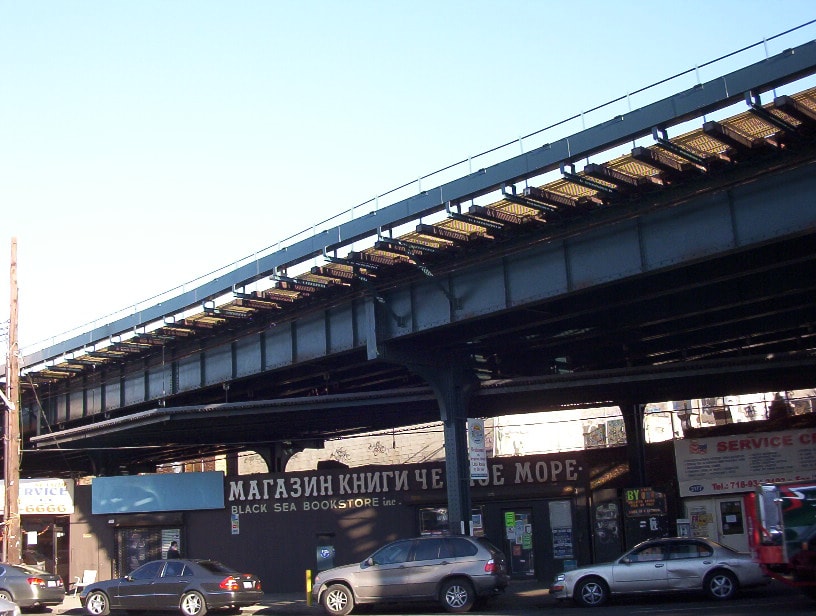 A storefront for the Black Sea Bookstore with Cyrillic lettering, located directly under the elevated subway line structure.