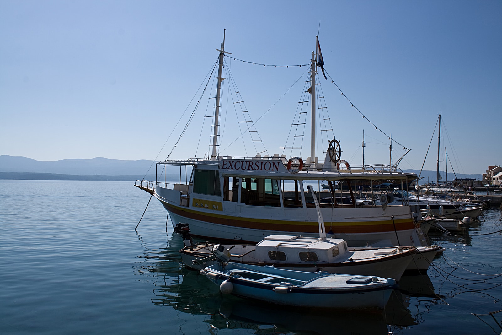 Traditional wooden passenger boats are moored in the clear blue water of Bol's harbor.