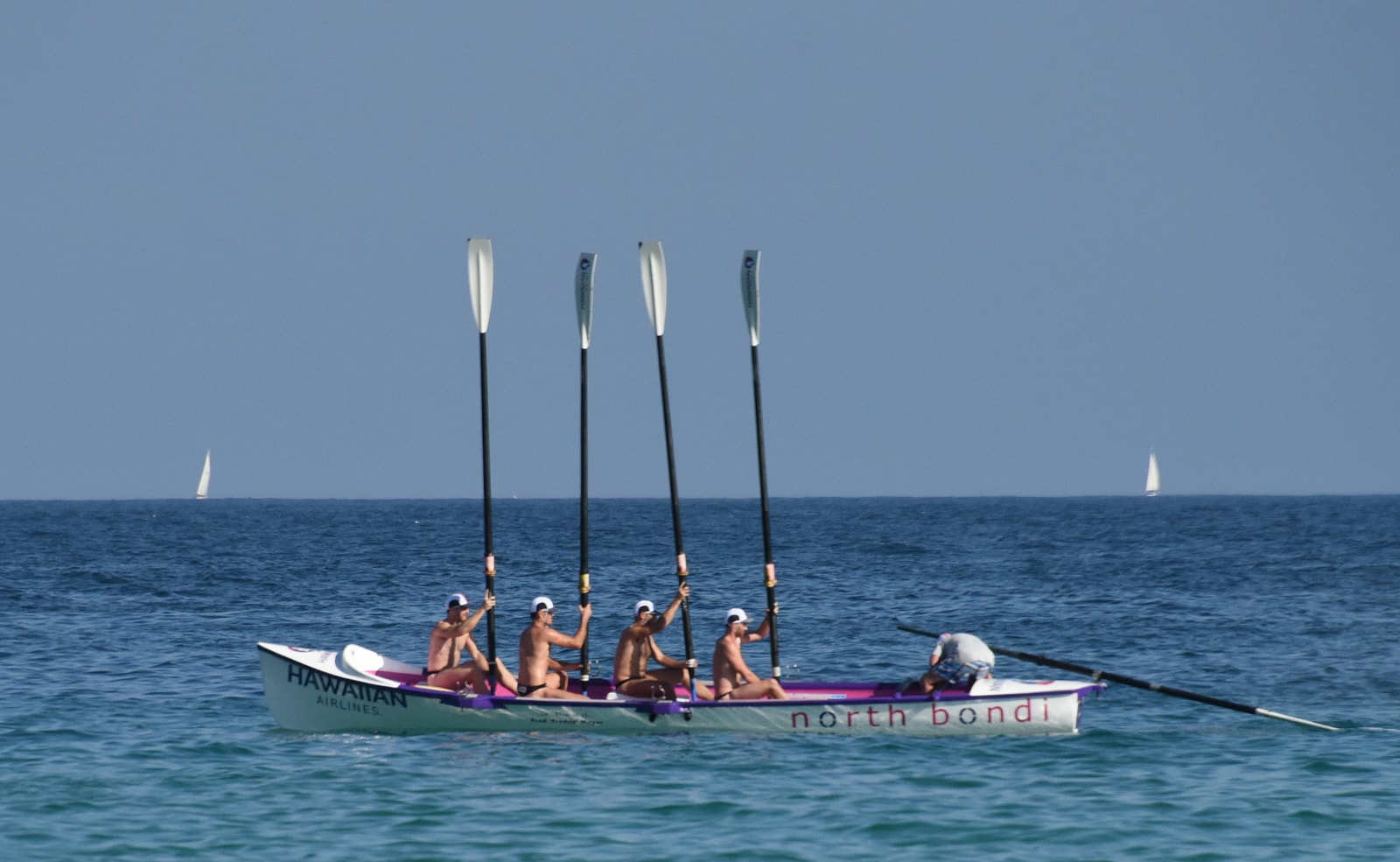 A team of surf lifesavers prepares to launch their red and yellow boat into the surf at Bondi Beach.