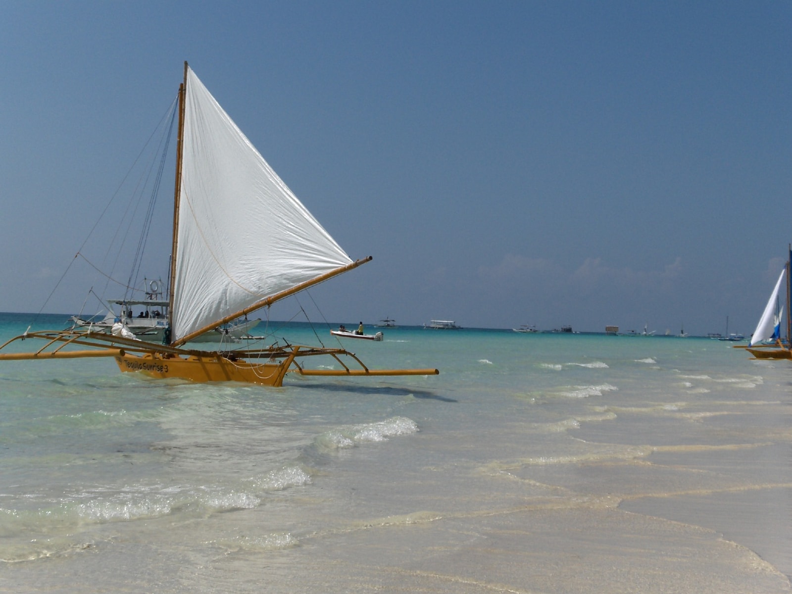 A close-up view of a traditional paraw sailboat on the water, with its distinct triangular sail.