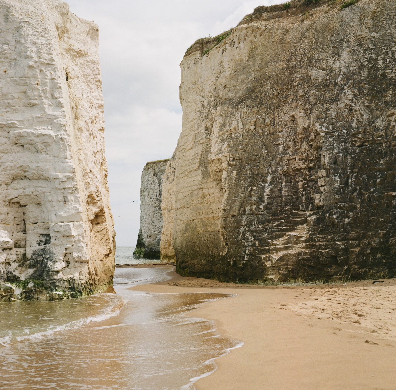 A view looking out to sea from between two towering white chalk cliffs at Botany Bay.