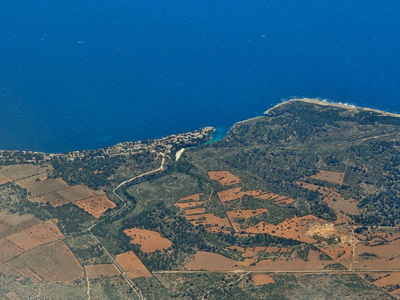 An aerial view of Cala Pi, showing the deep inlet cutting into the rugged coastline and surrounding landscape.