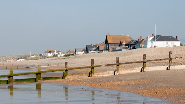 Modern, weather-boarded beach houses sit directly behind the dunes at Camber Sands.