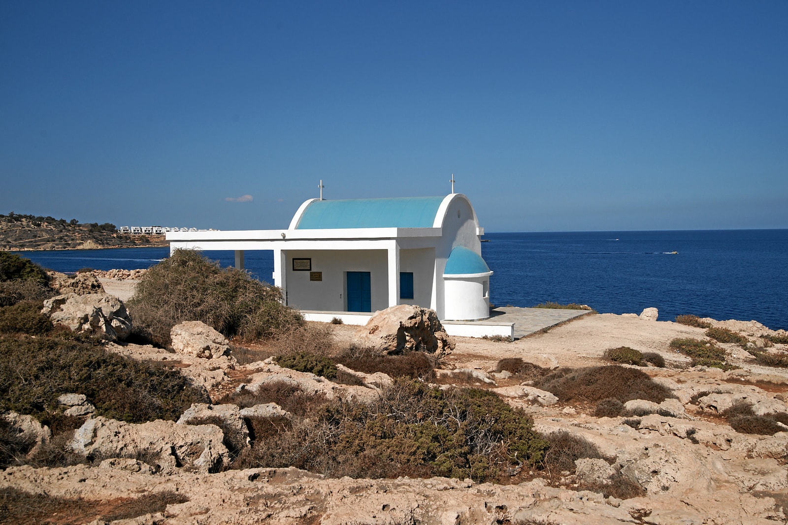 A blue-domed Greek Orthodox chapel, Agioi Anargyroi, sits on the rocky cliffs of Cape Greco near Ayia Napa.