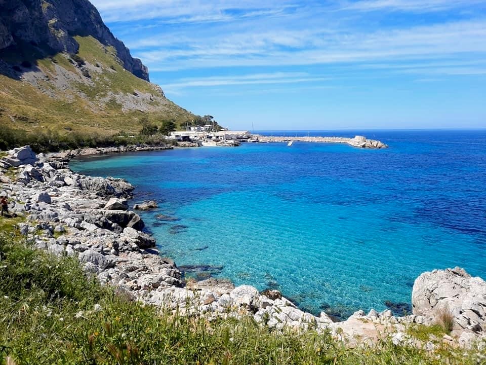 The rugged coastline of Capo Gallo, showing rocky shores meeting incredibly clear, turquoise water.