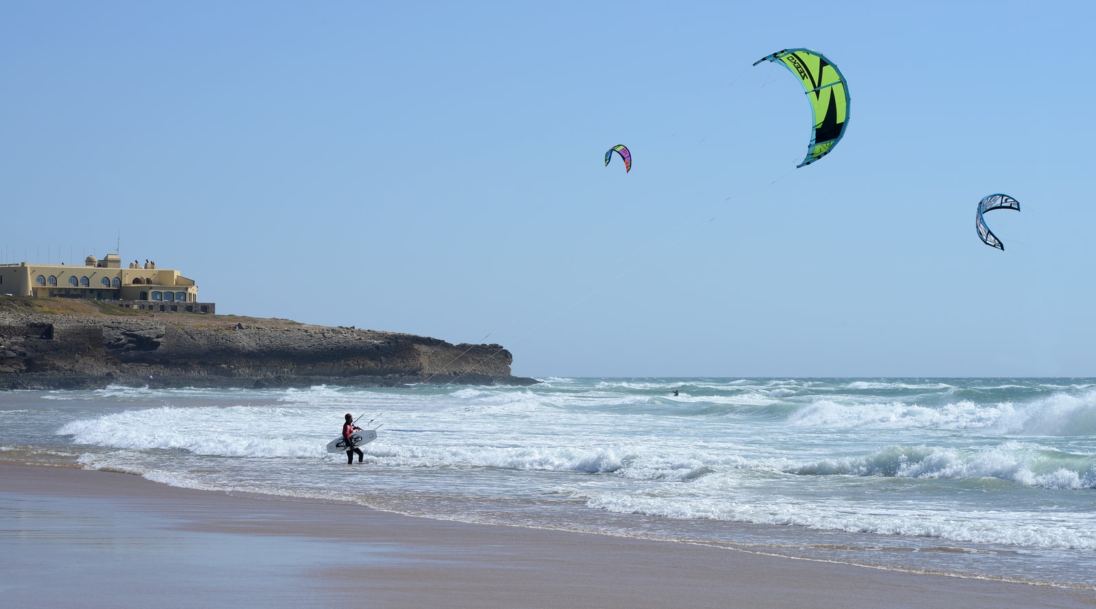 Kitesurfer catching air in high-action wind sports at windswept Guincho Beach in Cascais