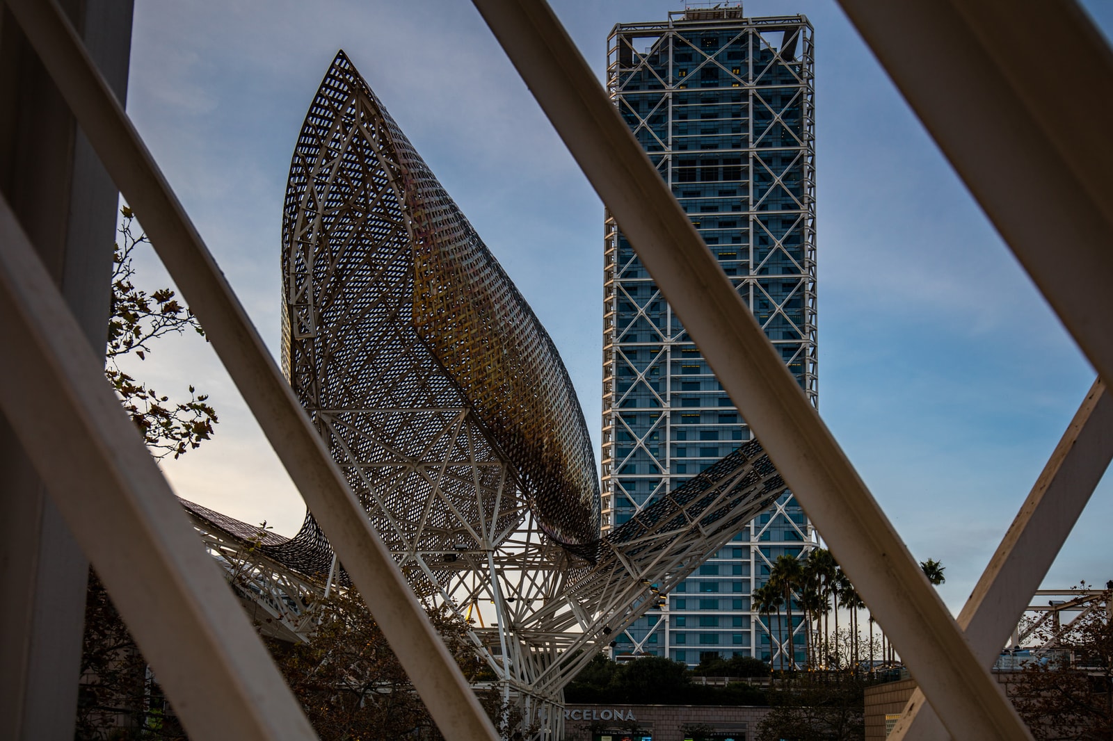 A view of Frank Gehry's golden fish sculpture framed by the modern architecture of the Casino Barcelona.