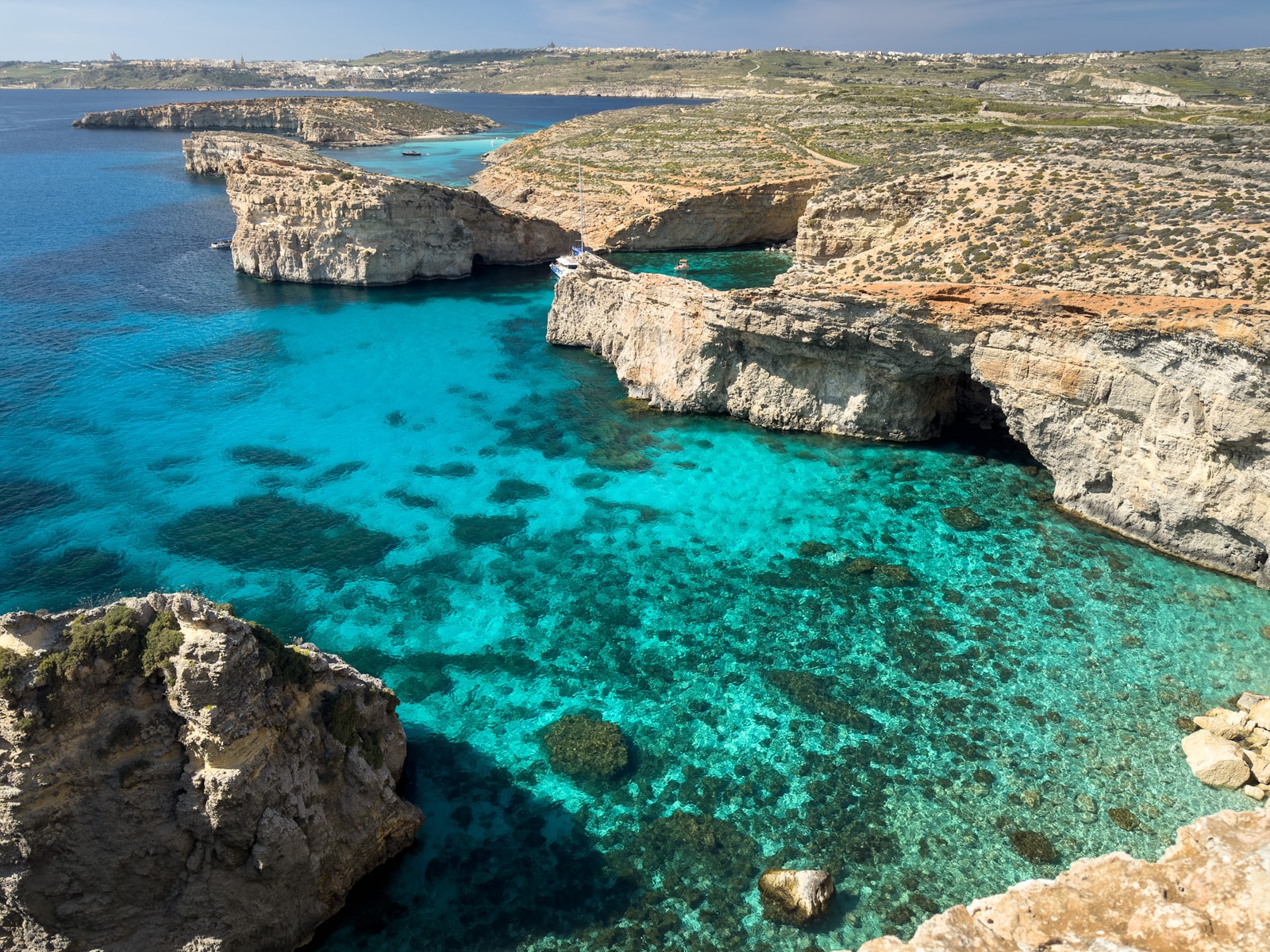 The deep turquoise water and sheer cliffs of Crystal Lagoon on Comino island.