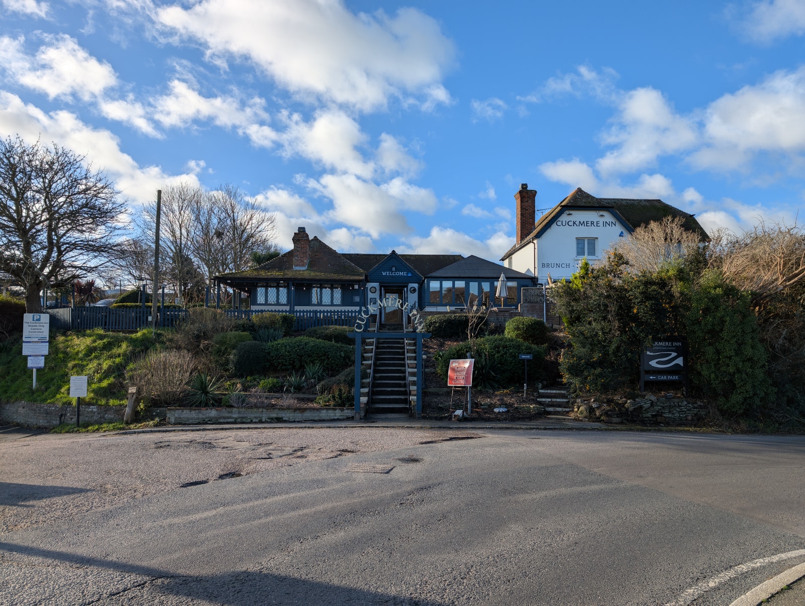 The exterior of The Cuckmere Inn, a traditional pub with white walls and a dark roof, located at Exceat Bridge.