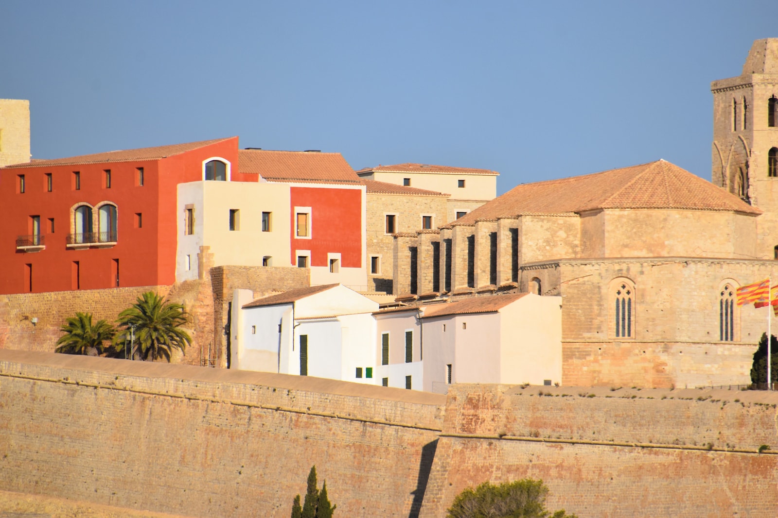 A view of Ibiza's historic walled city and cathedral, illuminated by golden hour light.