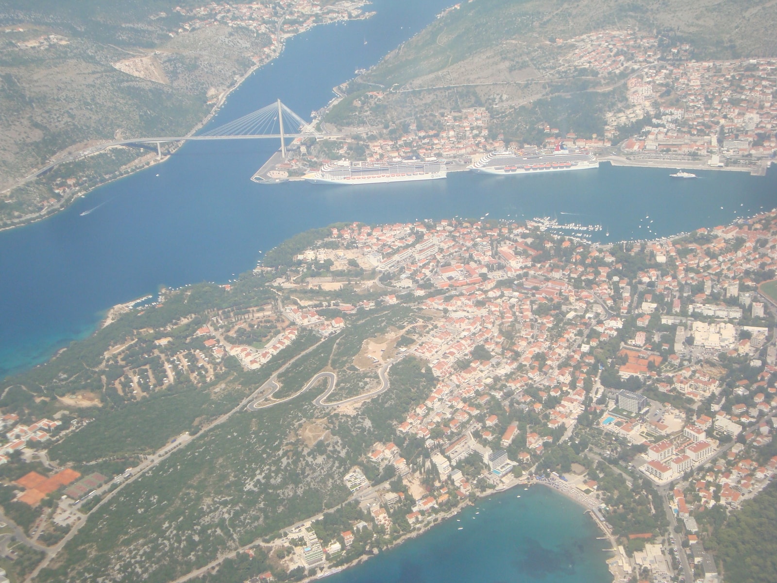 An aerial view shows the Lapad peninsula with its green spaces and surrounding water.