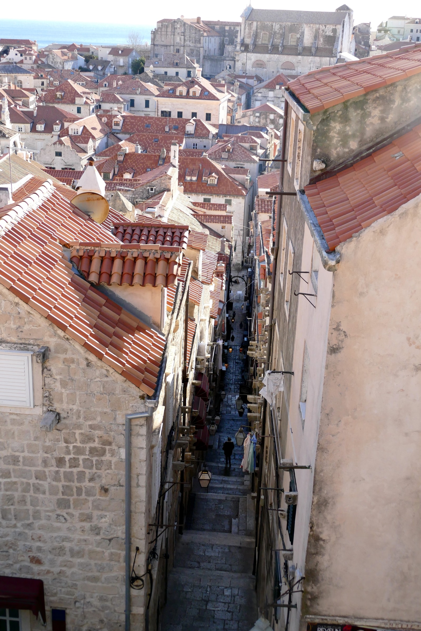 A steep, stepped street in Dubrovnik's Old Town, looking down towards other buildings.