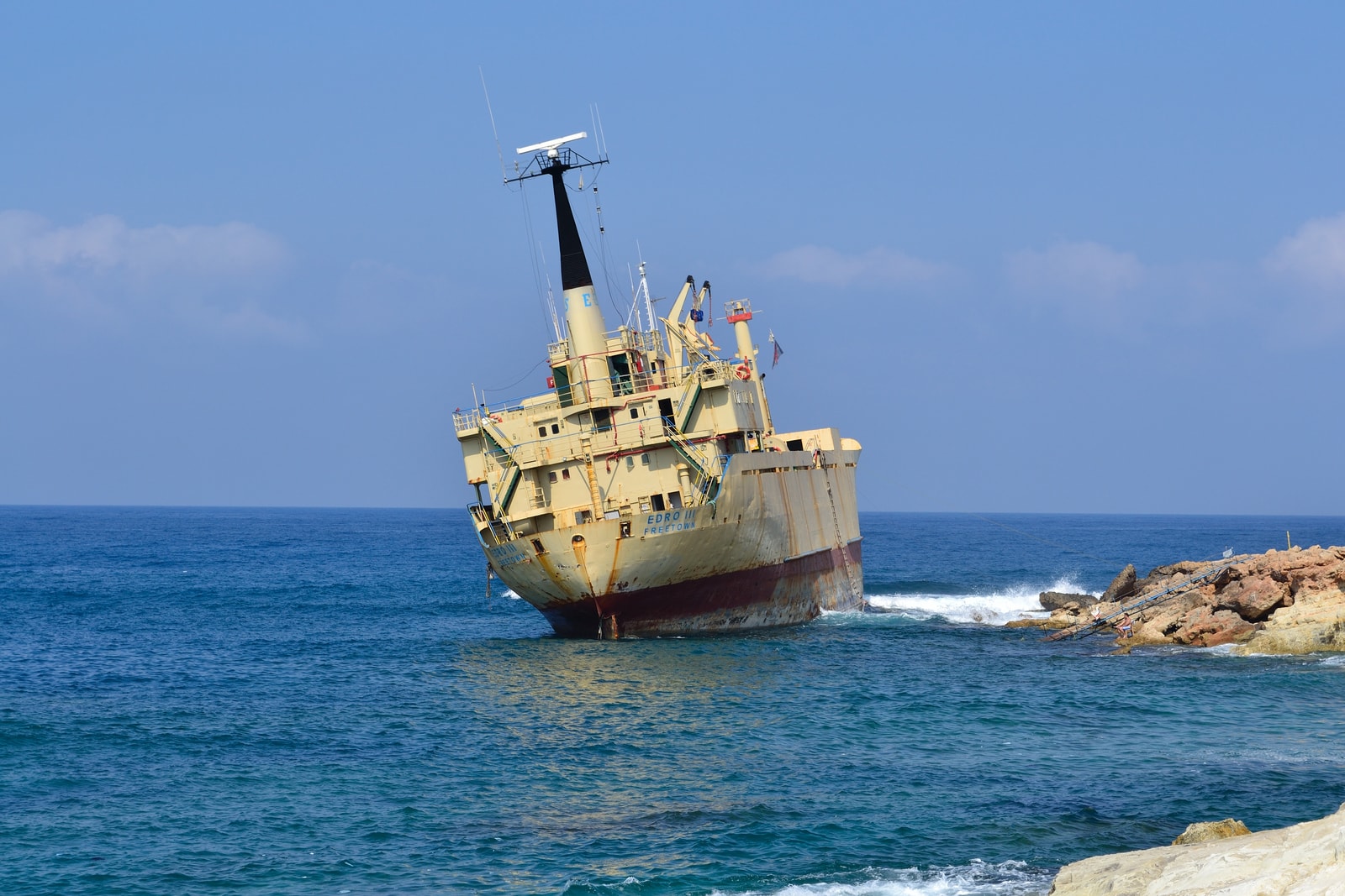 A clear, vivid photo of the grounded Edro III shipwreck against a backdrop of the bright blue sea.