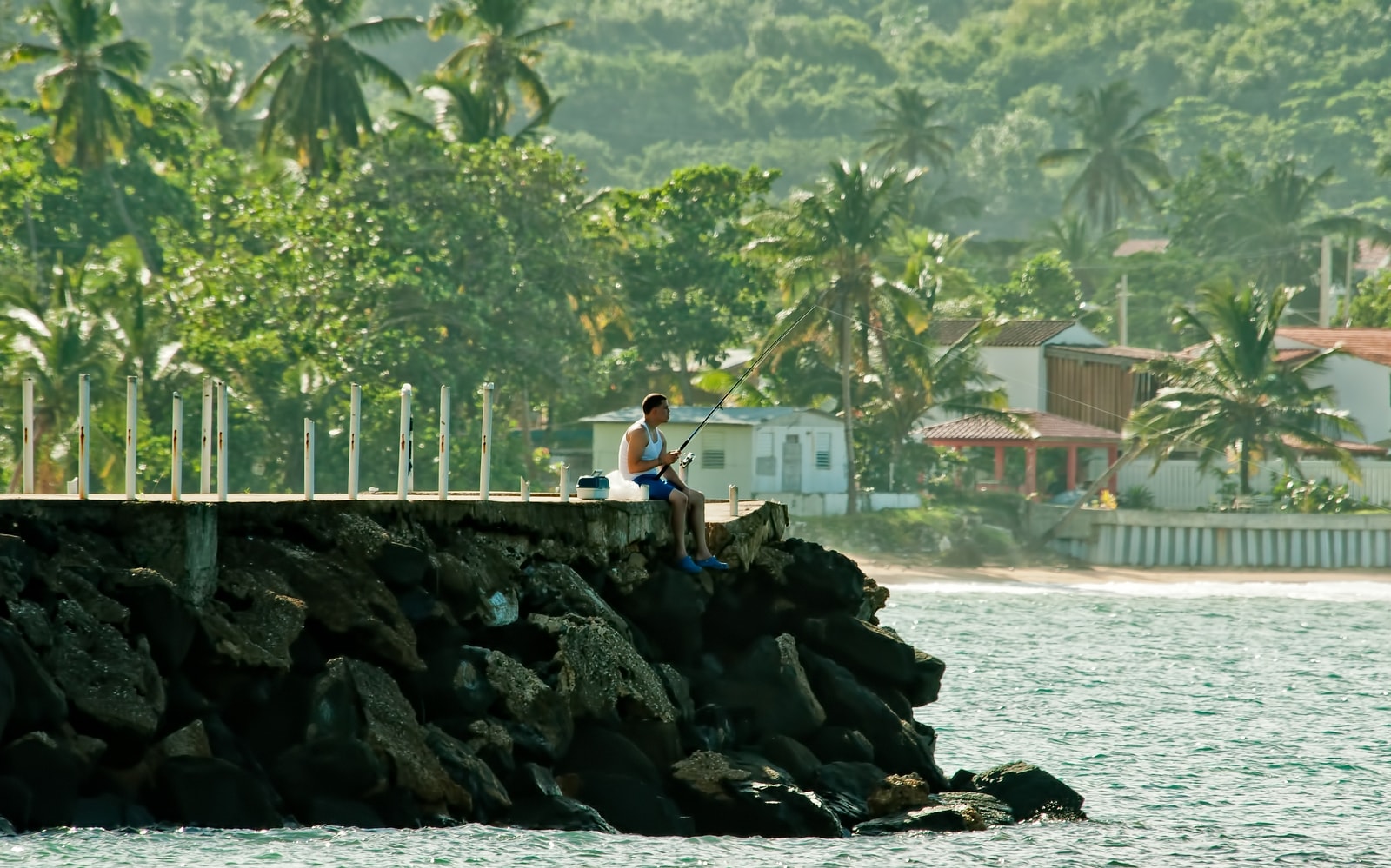 A person is silhouetted while fishing from the shore at sunset in Luquillo, Puerto Rico.