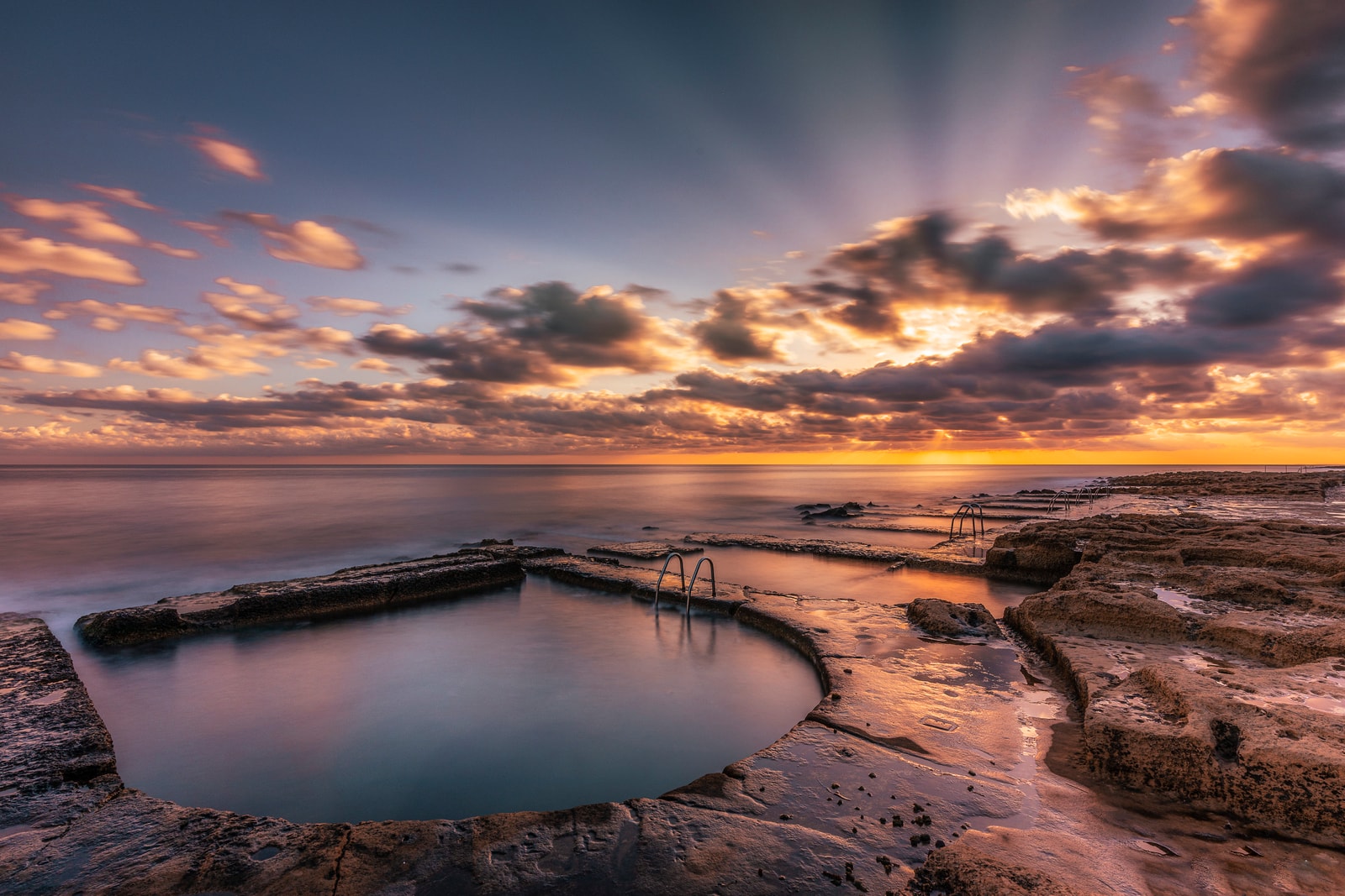 Rectangular pools, known as the Victorian Baths, carved into the flat limestone shoreline of Fond Għadir in Sliema.