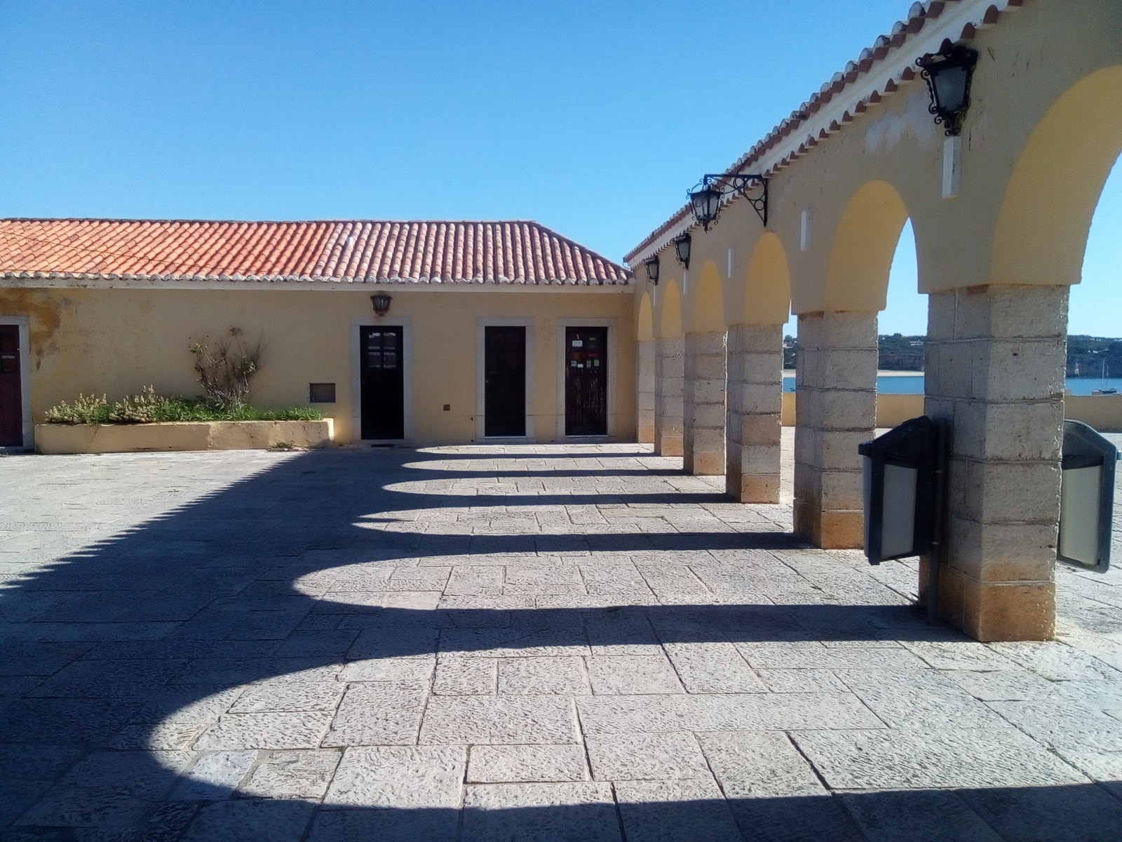 Sunlit stone arcades inside the Fortaleza de Santa Catarina, with strong shadows creating a repeating pattern.