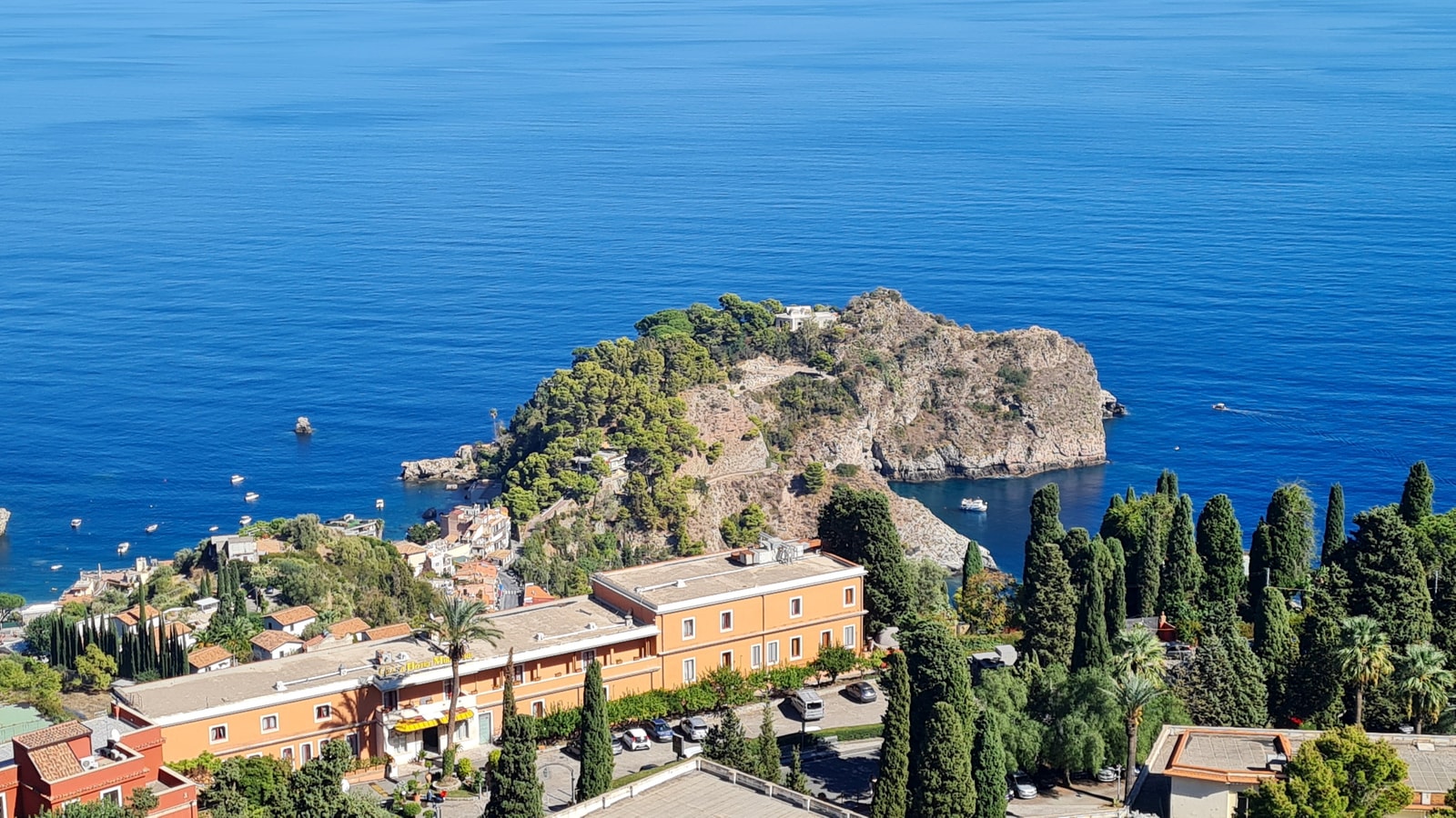 A view from the historic Greco-Roman theatre in Taormina, looking down at the coastal resorts nestled between the hills and the deep blue Ionian Sea.