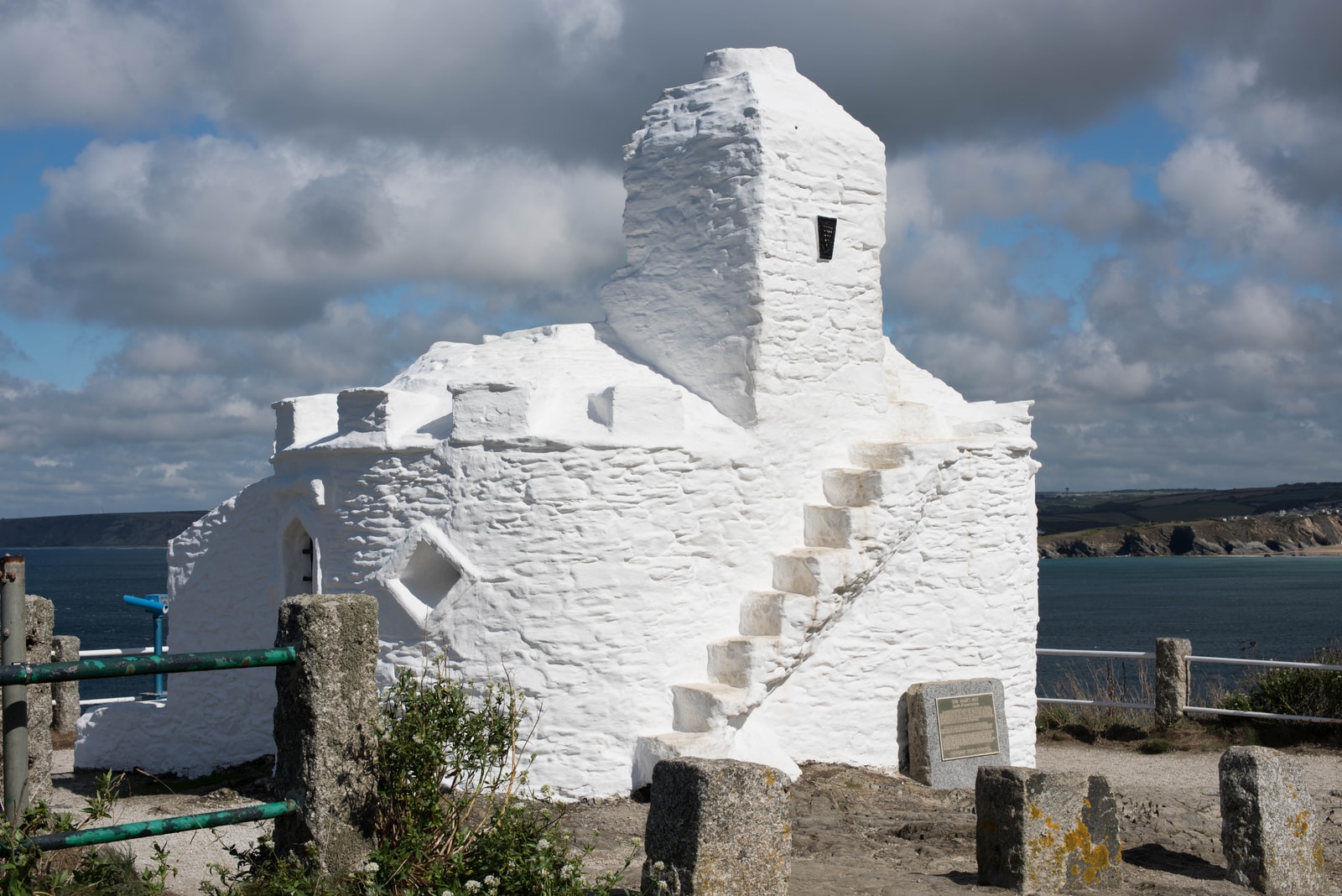 The whitewashed, circular Huer's Hut stands on a grassy clifftop overlooking the blue sea.