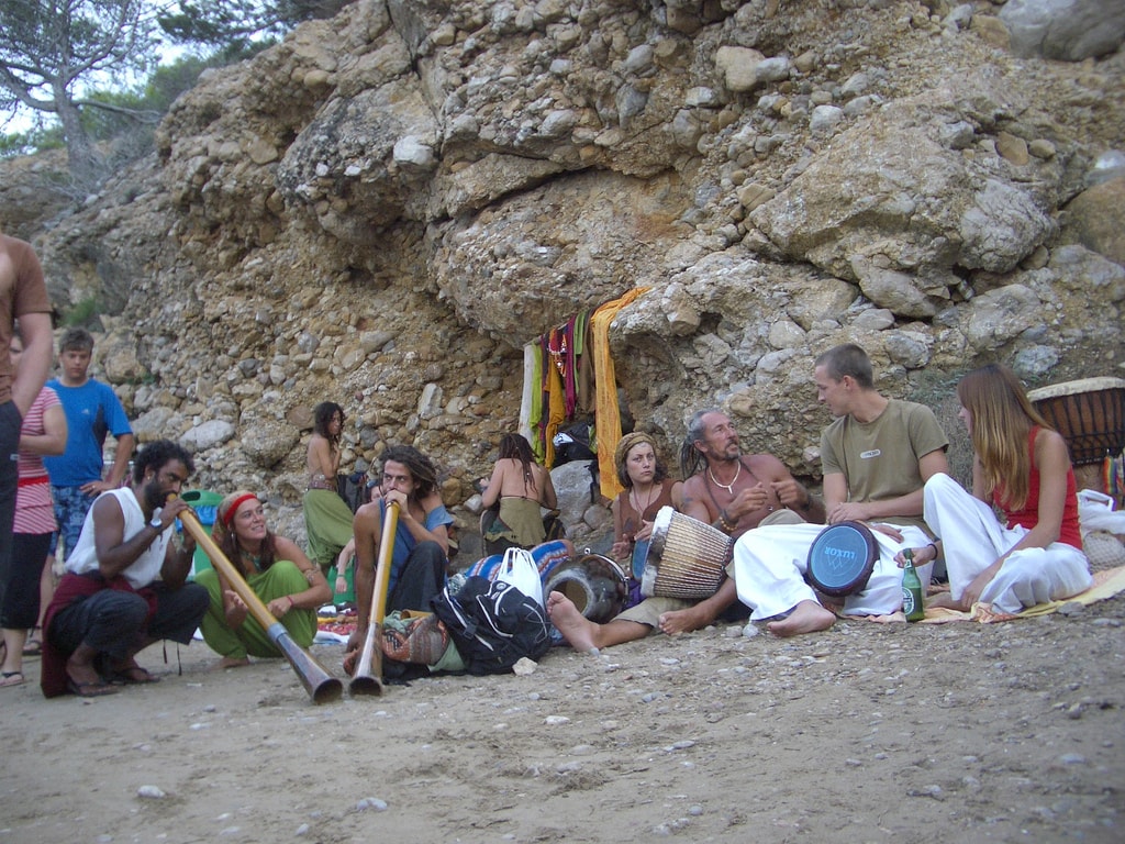 A lively scene of the sunset drumming ritual at Benirràs beach, with bohemian gatherers playing djembe drums to celebrate the setting sun.