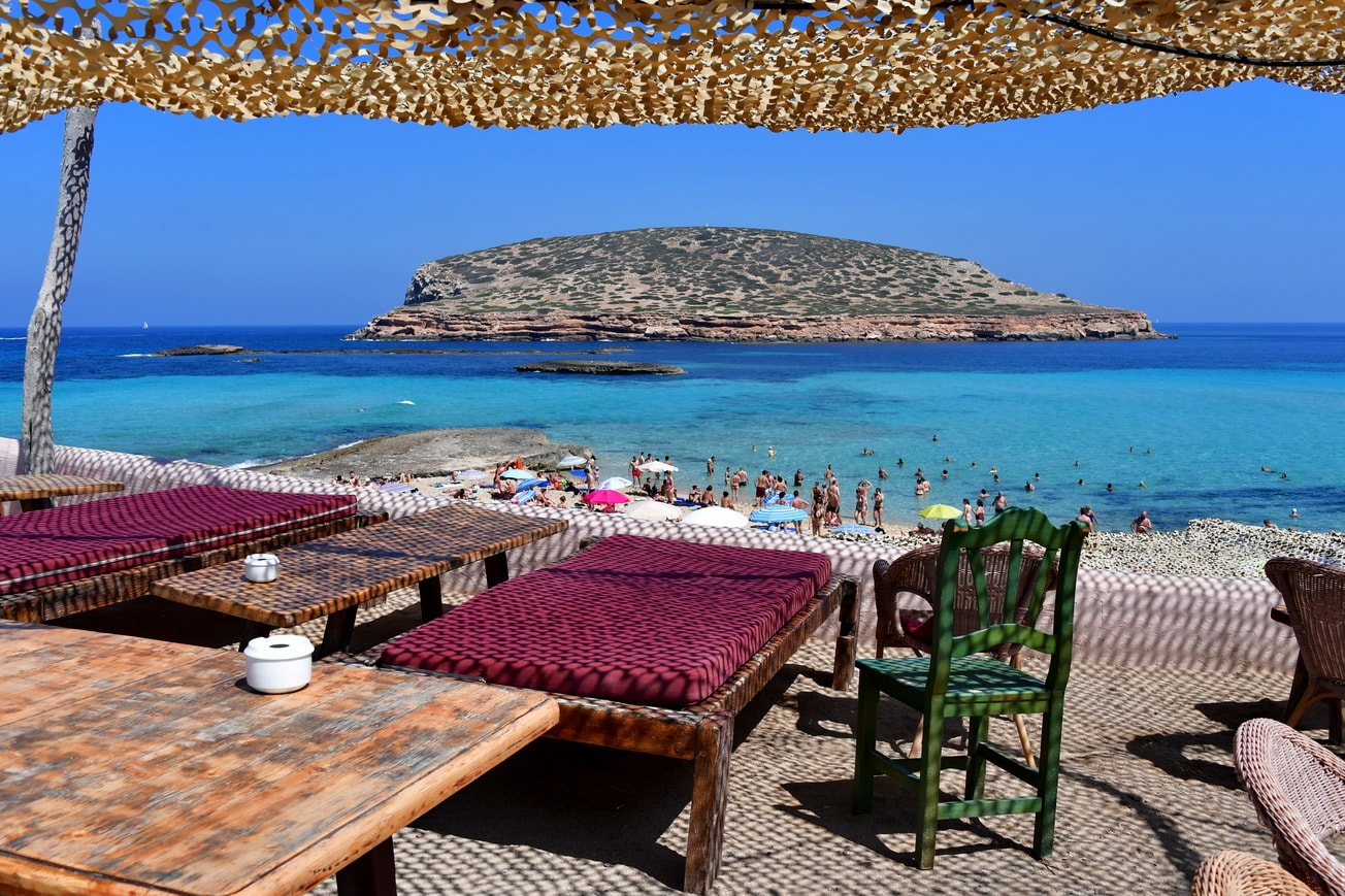A beautiful outdoor shaded deck looking down on a busy beach and crystal-clear turquoise waters.