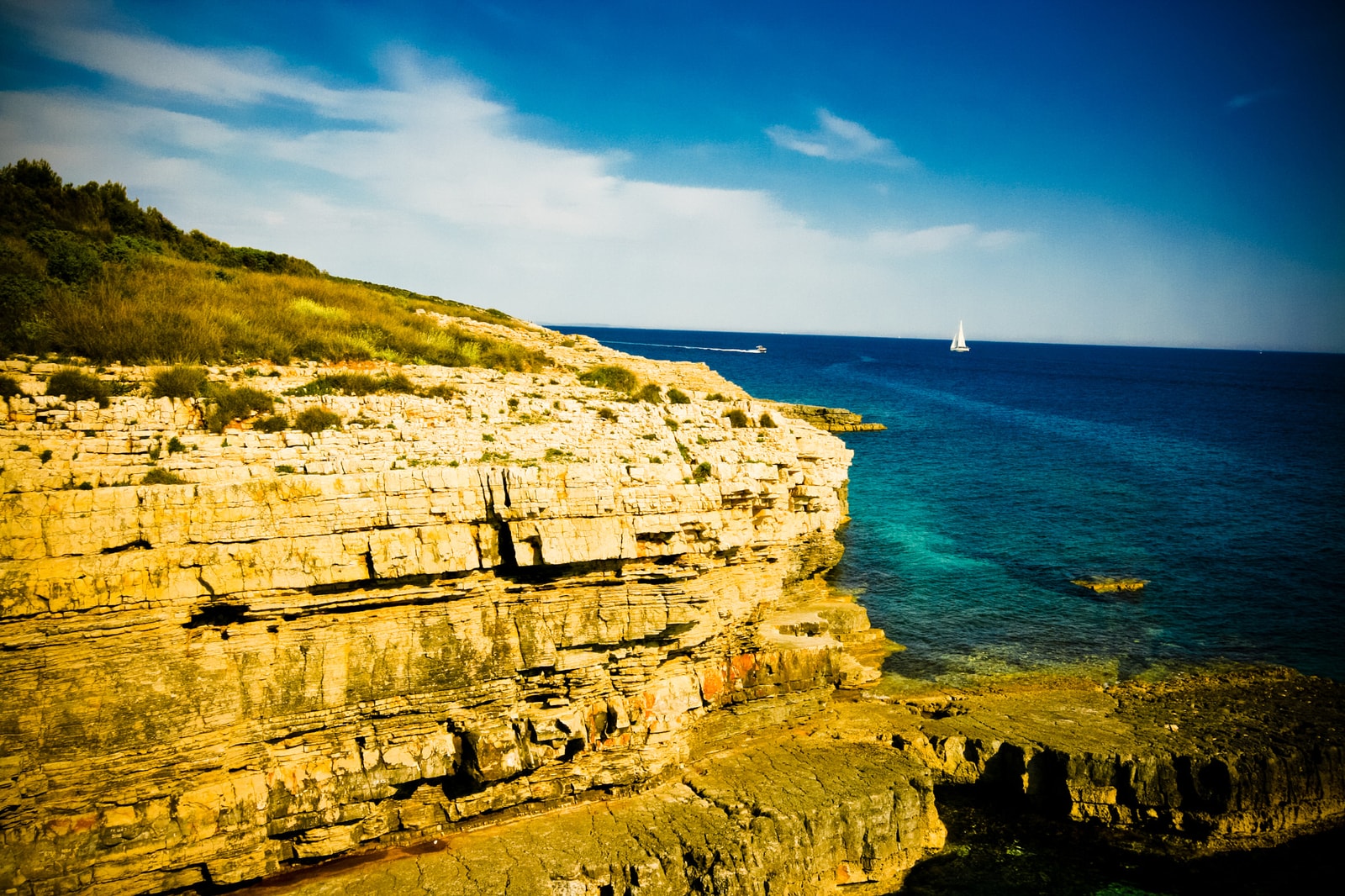 Dramatic, layered limestone cliffs glow golden in the sunlight at Cape Kamenjak on Croatia's Istrian peninsula.