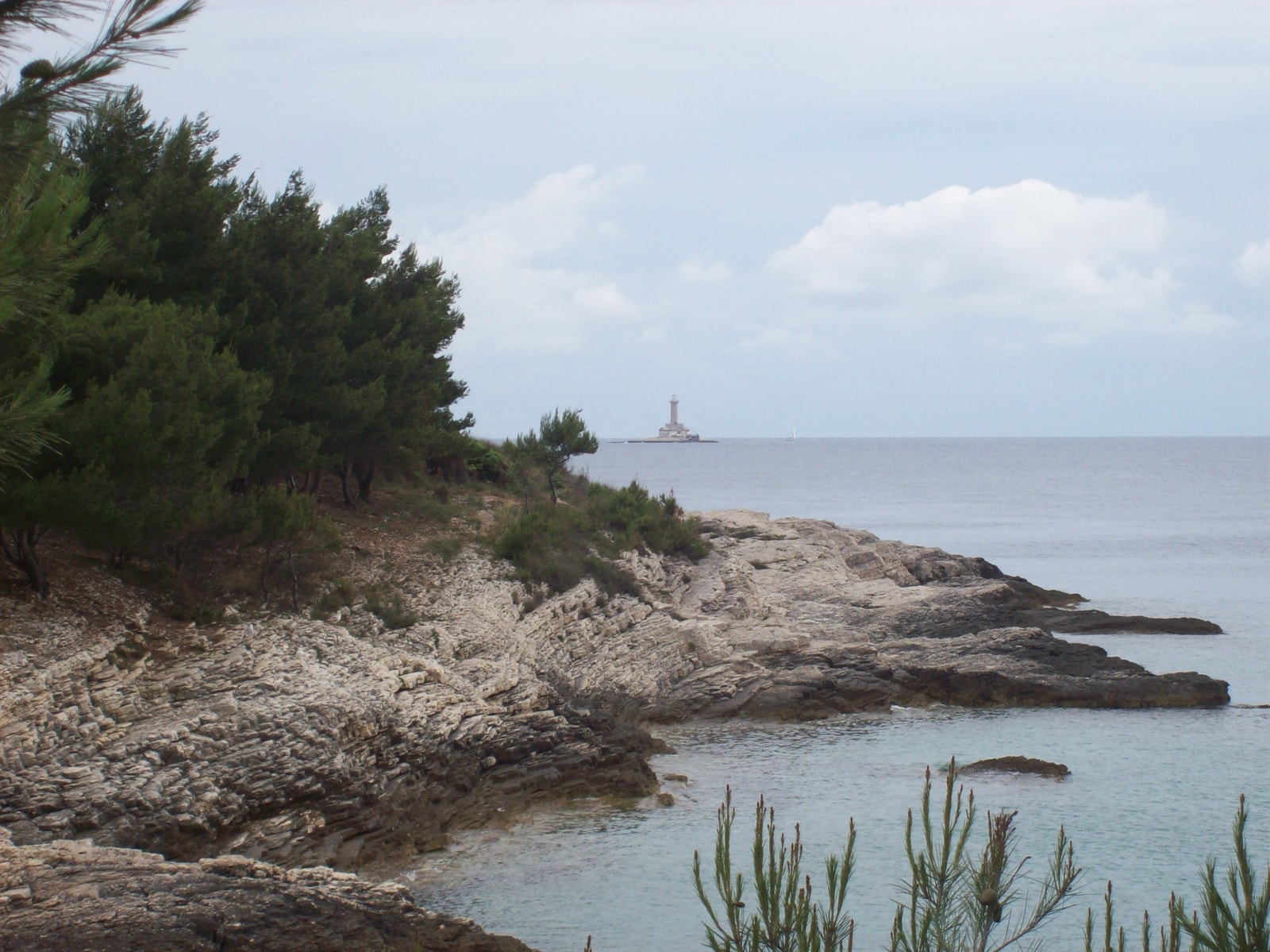A view across the rugged coastline of Cape Kamenjak towards the distant Porer lighthouse islet on the horizon.
