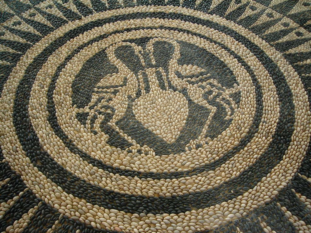 A close-up of a detailed pebble mosaic floor in a concentric circular pattern.