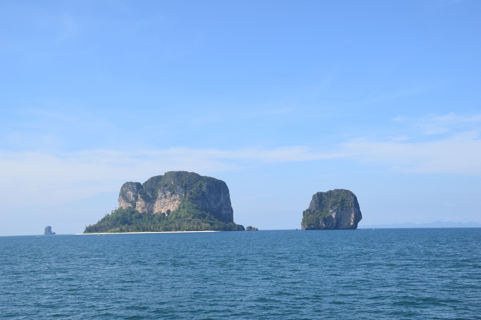 Two limestone karst islands, Ko Po Da Nai and Ko Ma Tang Ming, rise from the turquoise Andaman Sea under a clear sky.
