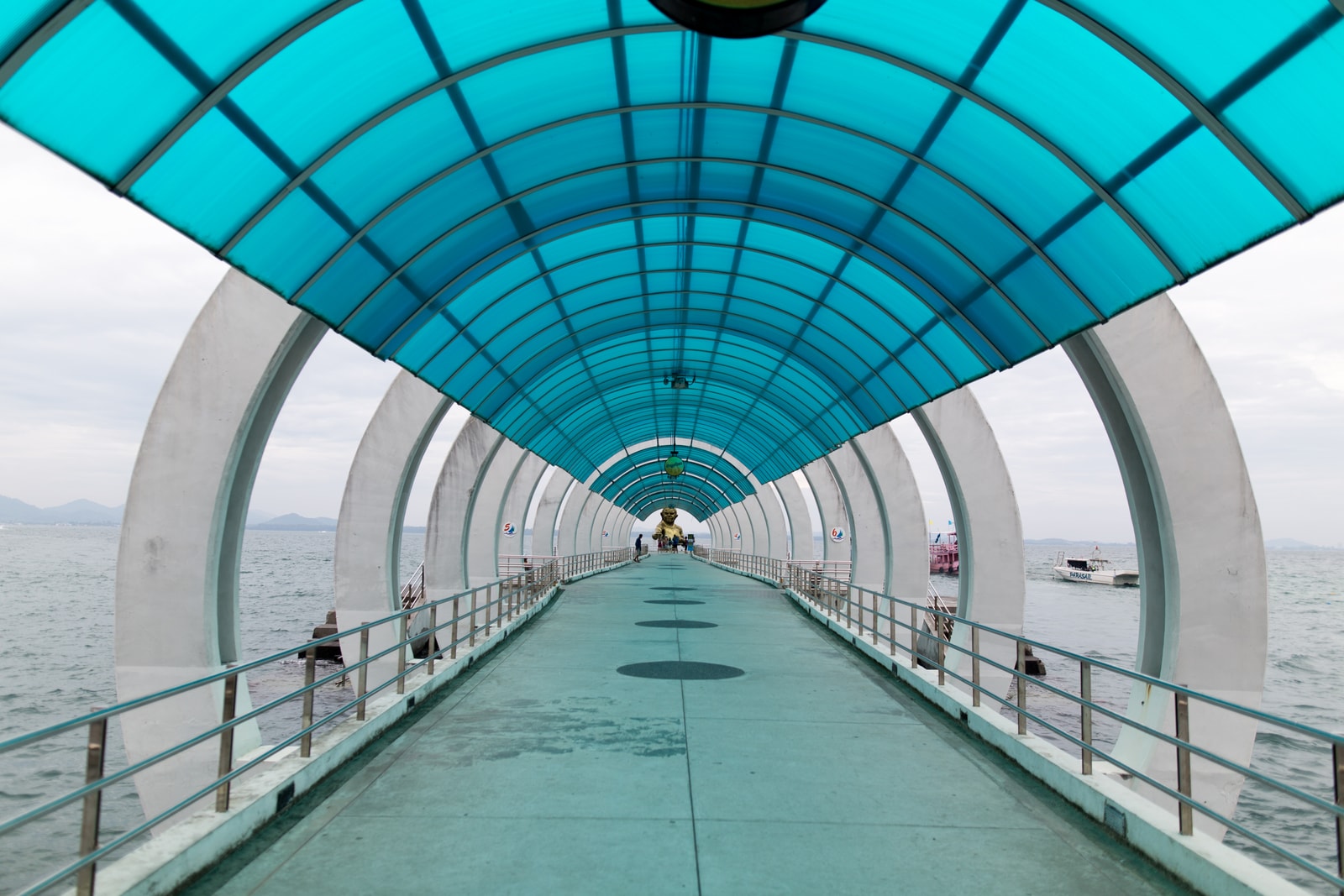 A symmetrical view down a long, covered pier extending over the water on Koh Samet.