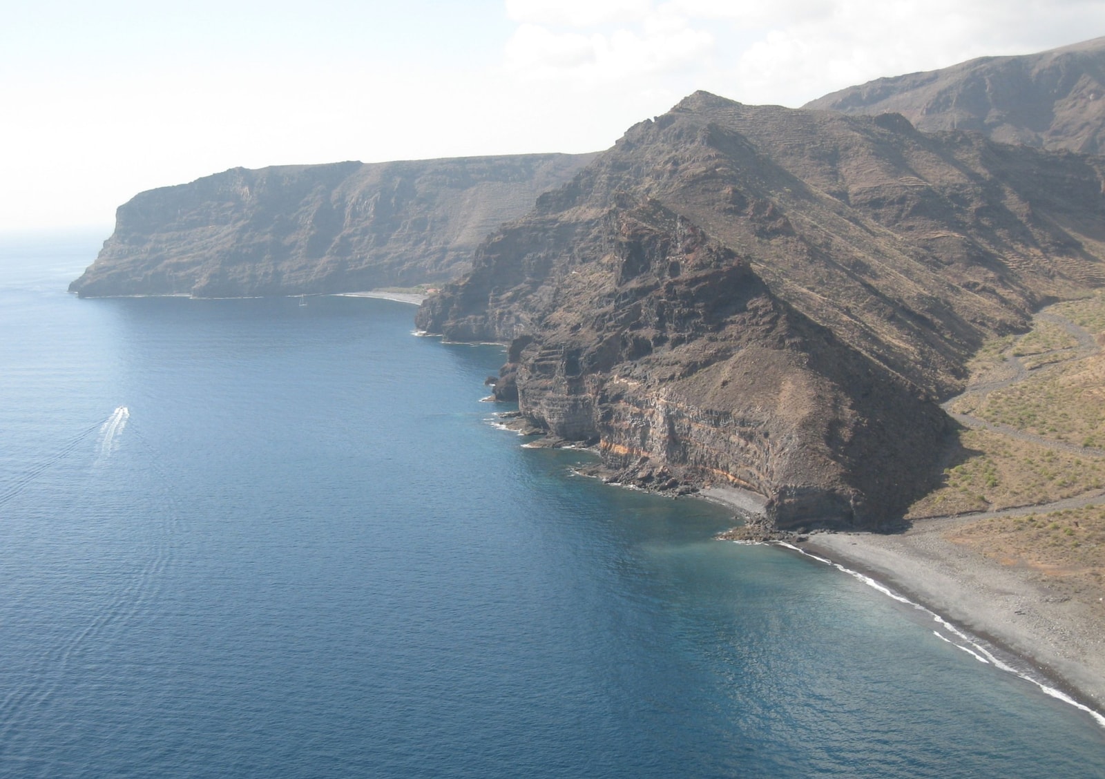 A sweeping view of La Gomera's steep southern coast, showing deep ravines and small coves meeting the Atlantic Ocean.