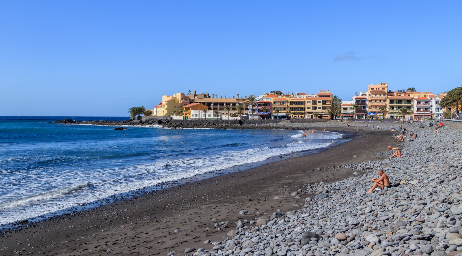 A broad view of a dark-pebble shoreline next to the coastal town of La Playa in Valle Gran Rey.