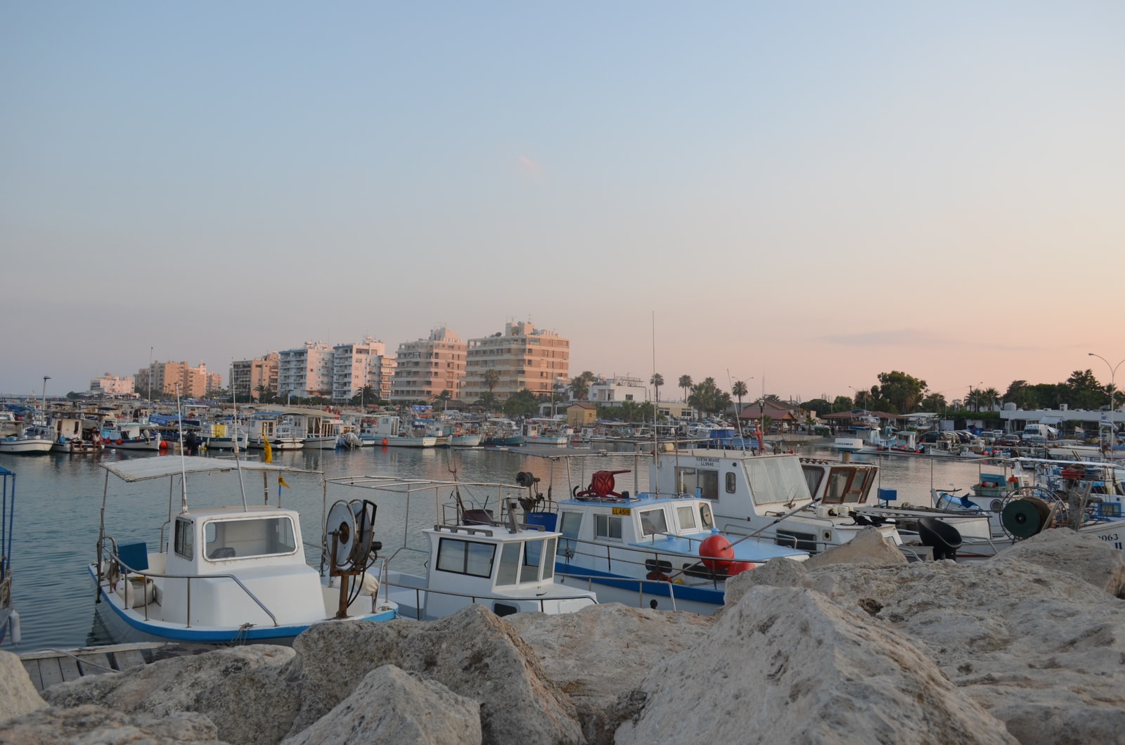 A view of the Psarolimano fishing port, with numerous small fishing boats moored in the calm water.