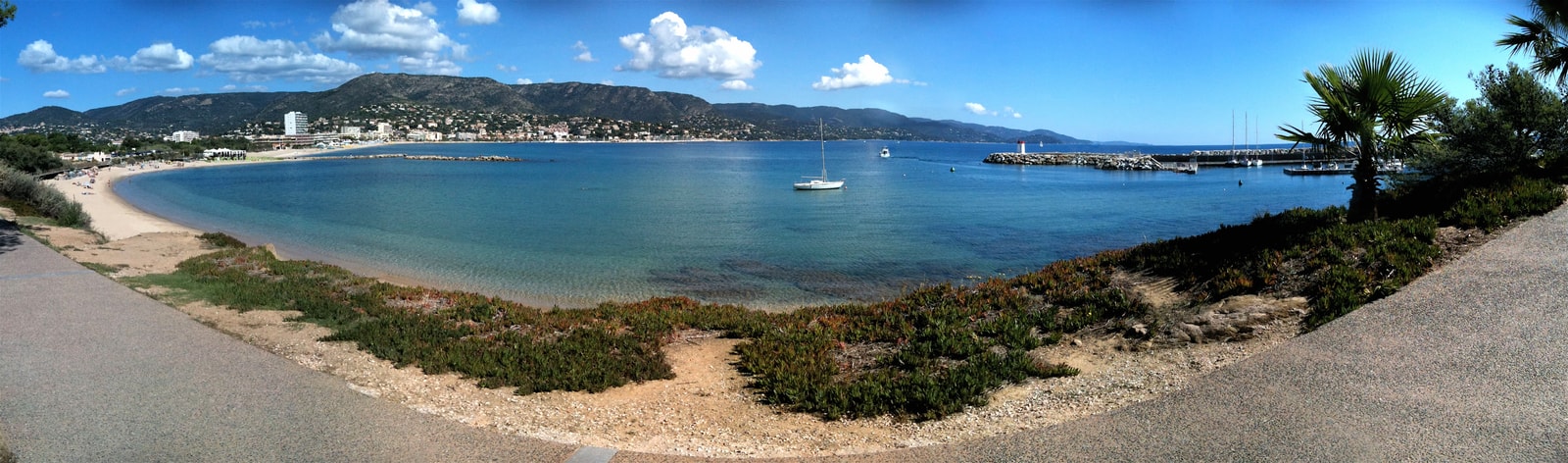 A wide panoramic view of Le Lavandou's coast, showing the marina, town, and mountains.