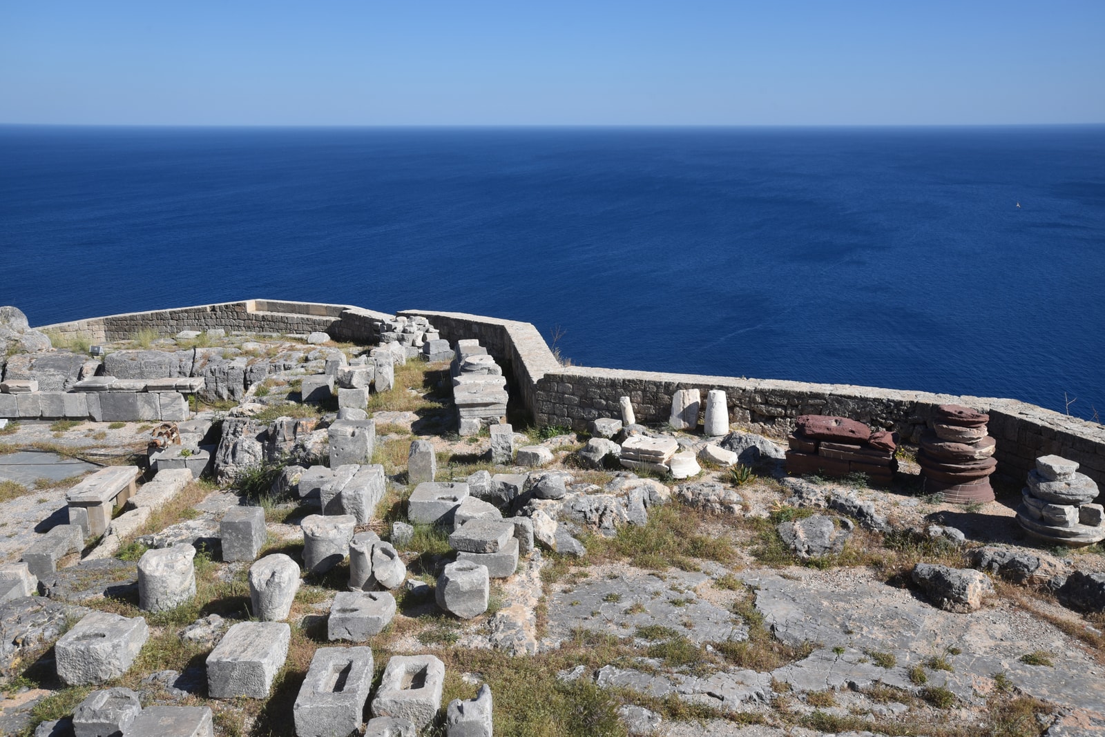 The ancient ruins of the Acropolis of Lindos sit atop a rocky cliff overlooking the deep blue sea.