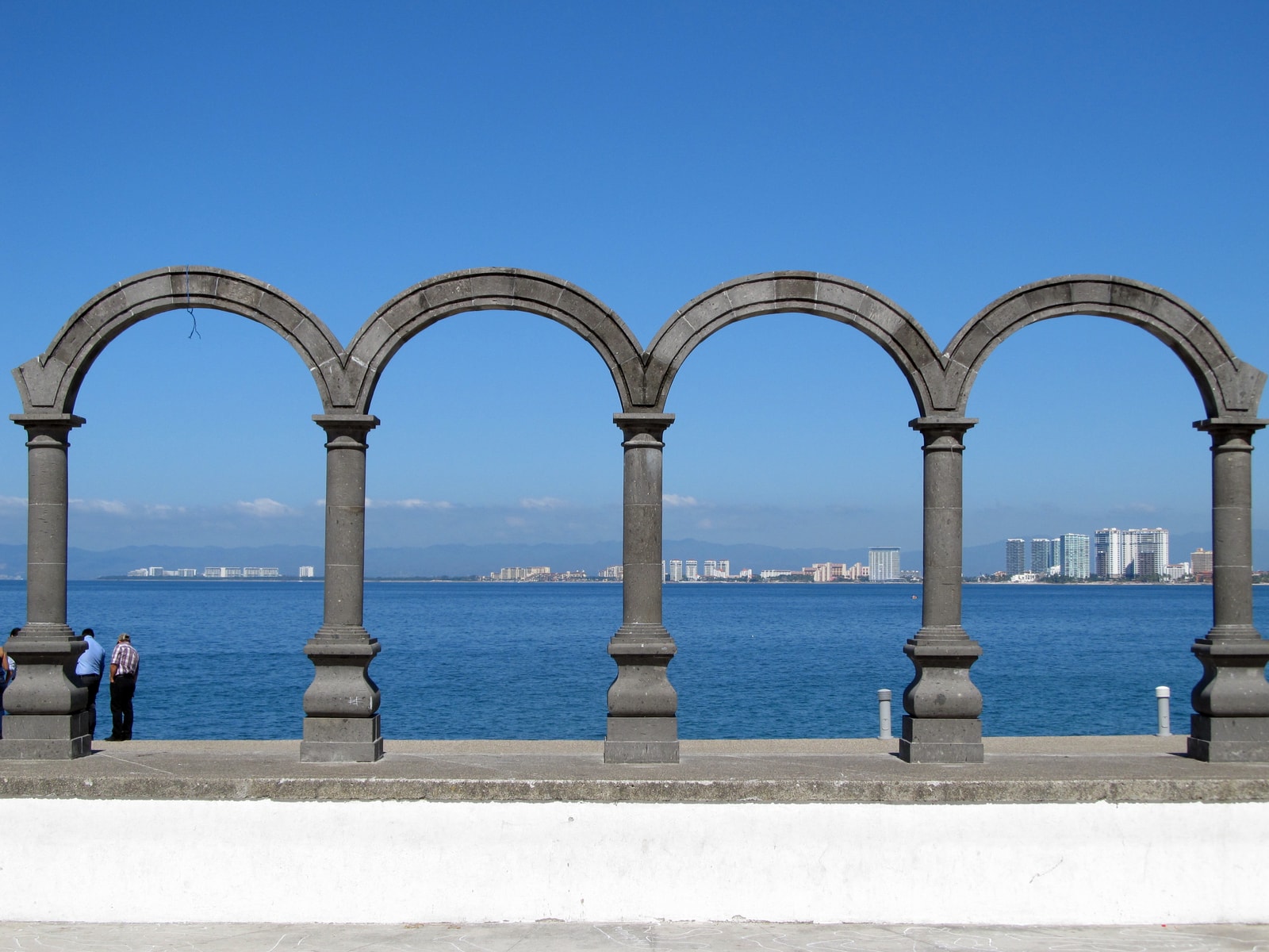 Large granite rock formations arching out of the blue water of Banderas Bay.