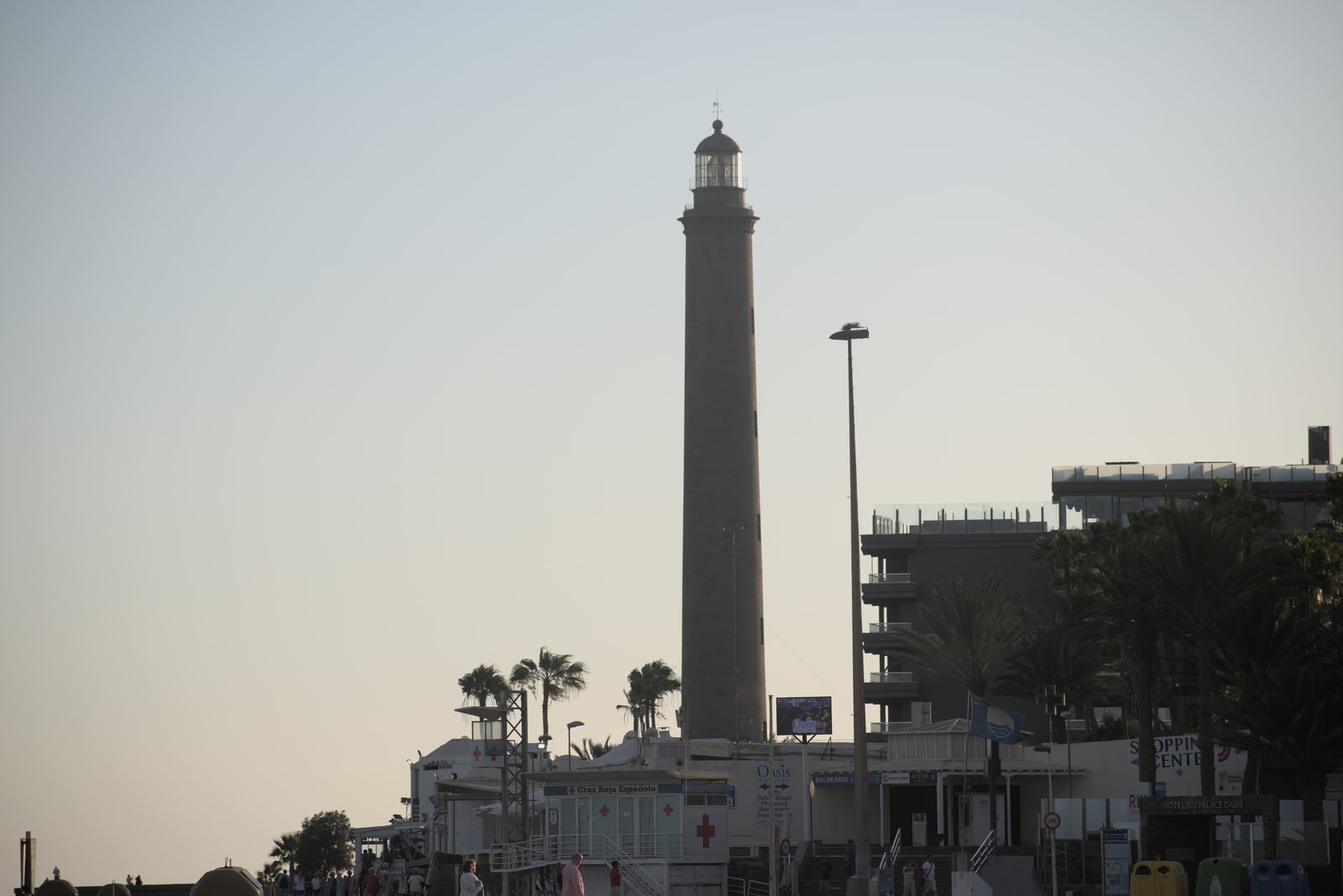 A close-up shot of the historic Maspalomas Lighthouse, showing its stone construction against a clear blue sky.