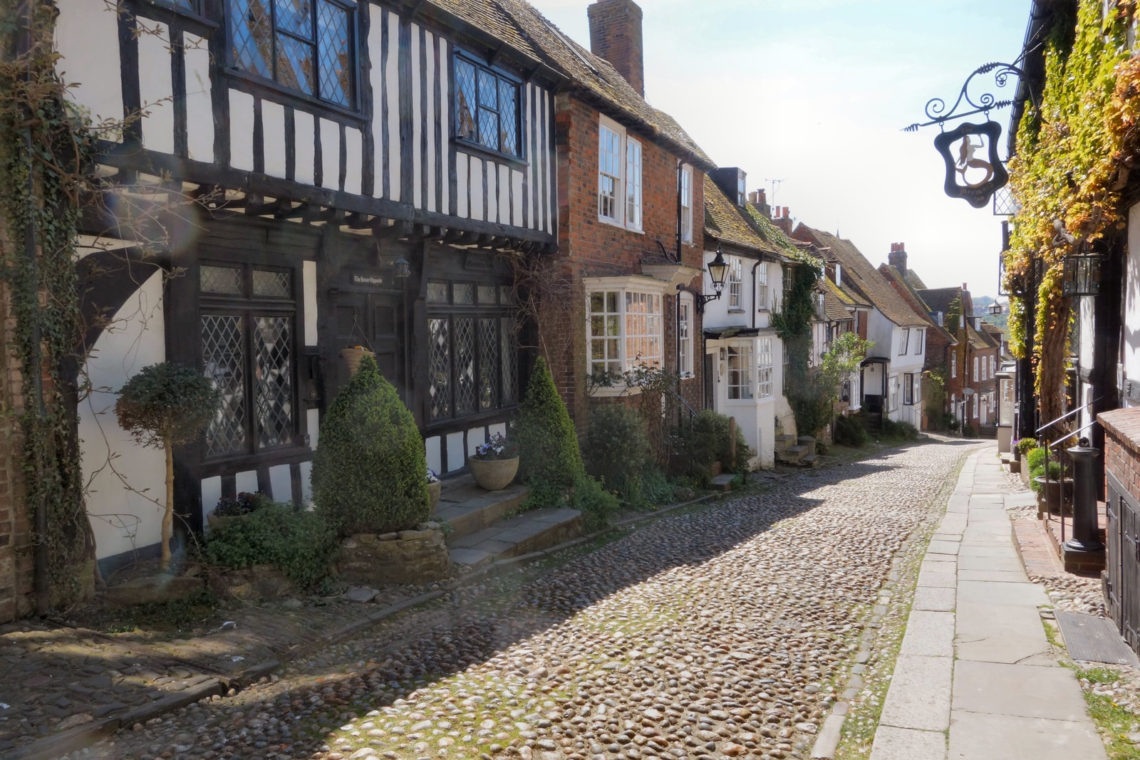 A cobblestone street curves uphill, lined with historic timber-framed medieval houses.