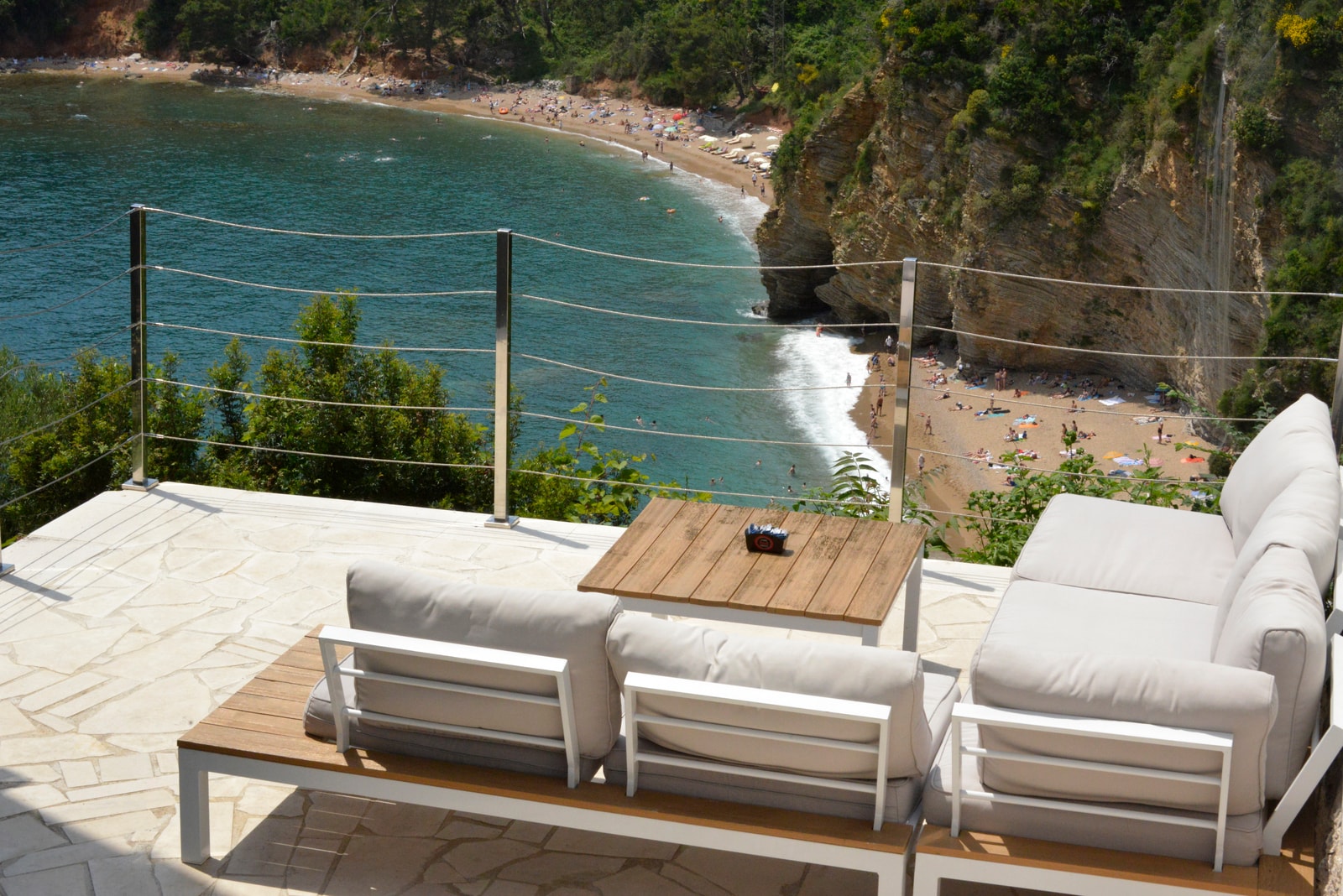 An elevated view shows two sandy coves, Mogren 1 and Mogren 2, nestled at the base of steep, rugged limestone cliffs.