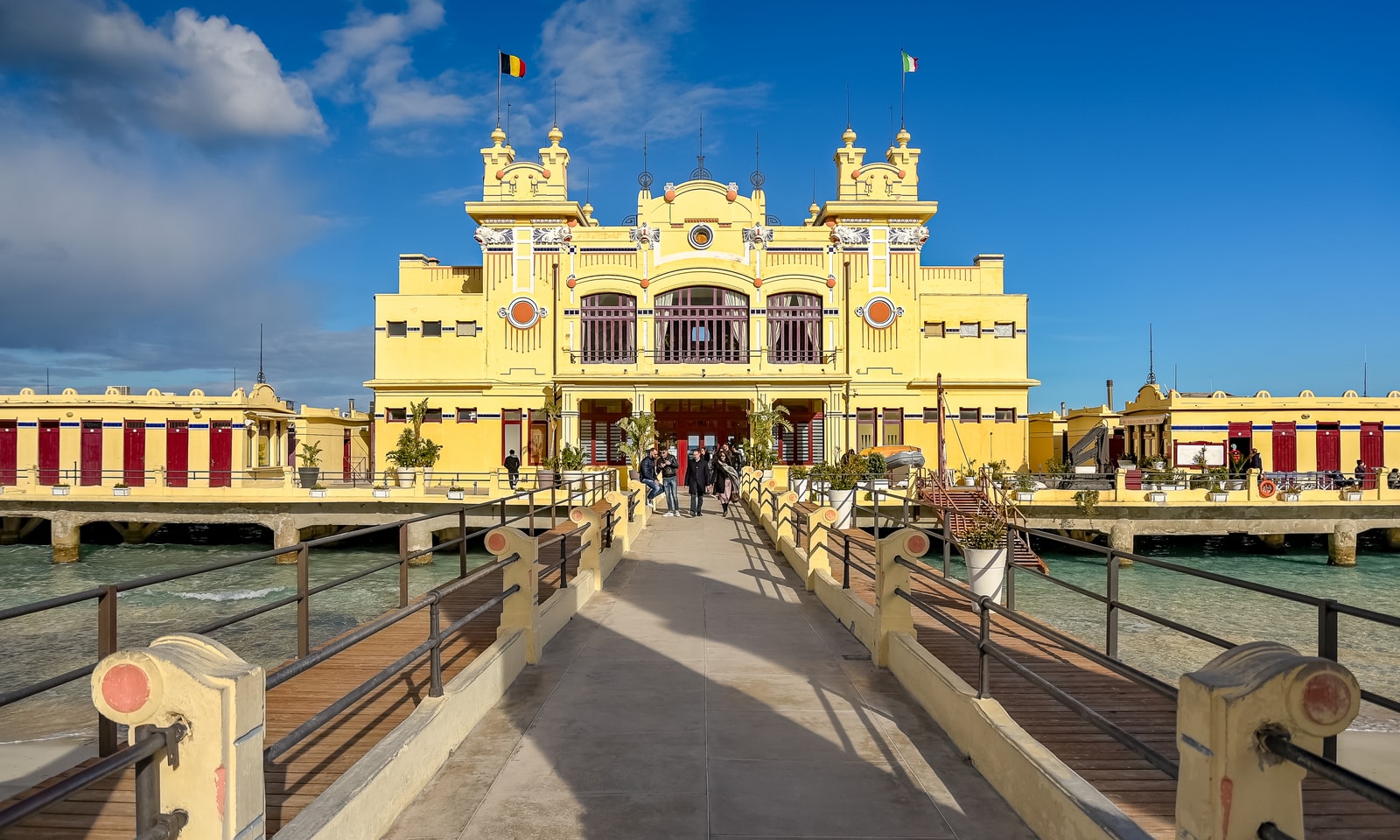 View from the wooden pier as people walk towards the Charleston restaurant, located in the Antico Stabilimento Balneare over the sea.