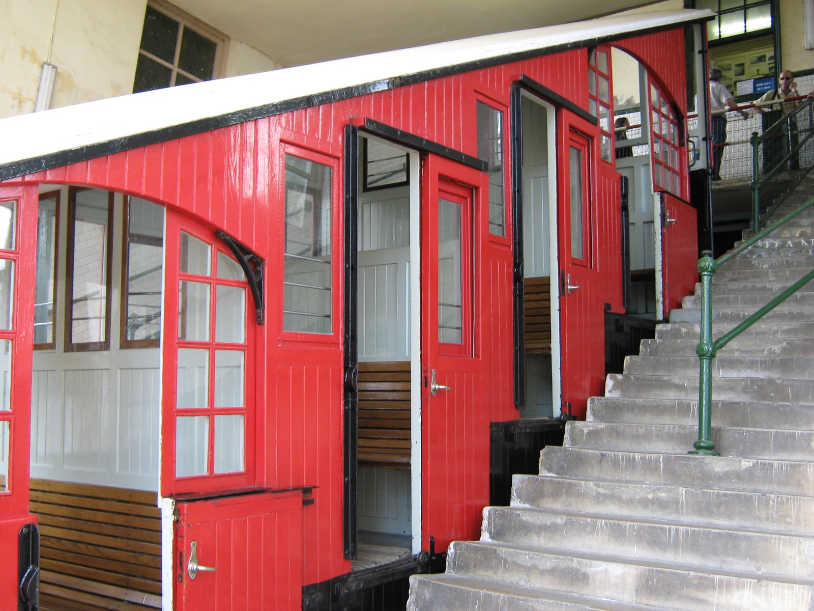The bright red wooden carriage of the historic Funicular de Igueldo on its tracks ascending the mountain.